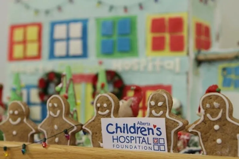 Gingerbread people lined up outside a colourful gingerbread building with a Children's Hospital sign