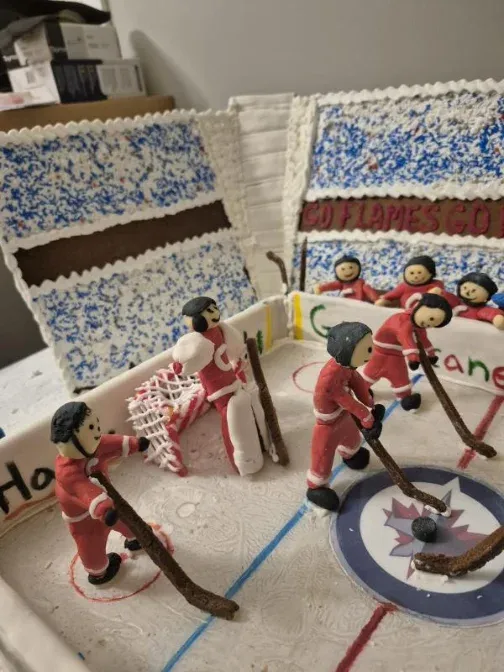 Gingerbread shopfront with a wreath over the sign and a red candy path through the snow