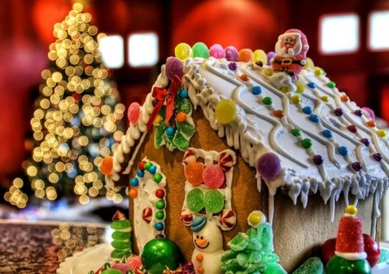 Close-up of a gingerbread house with thick white icing, gumdrops and a Santa figure on the roof