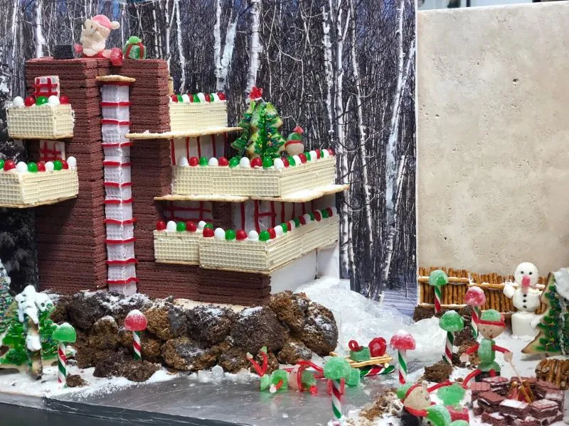 Tall layered gingerbread tower with wafer balconies and chocolate-rock landscaping in snow