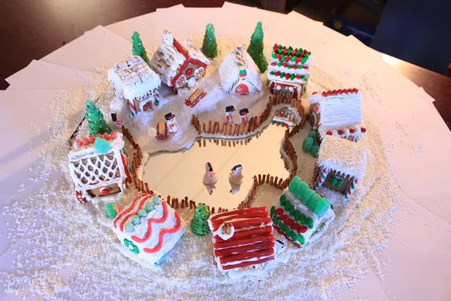 Ring of small white gingerbread houses around a central courtyard on a snowy board