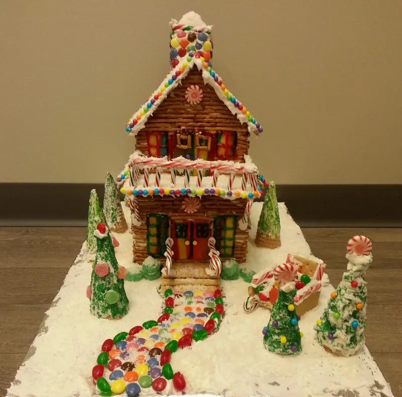 Two-storey gingerbread house with a candy-studded path, frosted trees and snowman figures