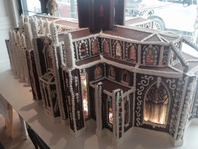 Large gingerbread cathedral with lit arched windows, spires and white piped detailing