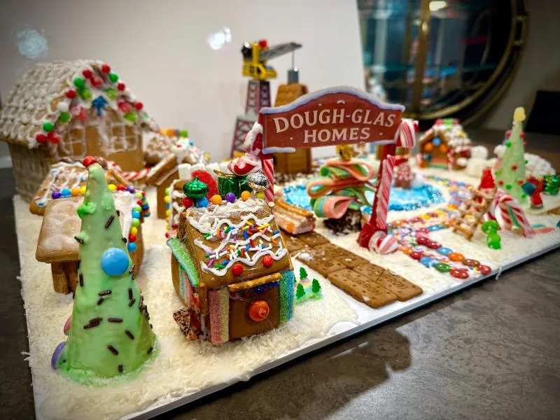 Dough-glas Homes gingerbread neighbourhood with a sign, candy houses and a green cone tree